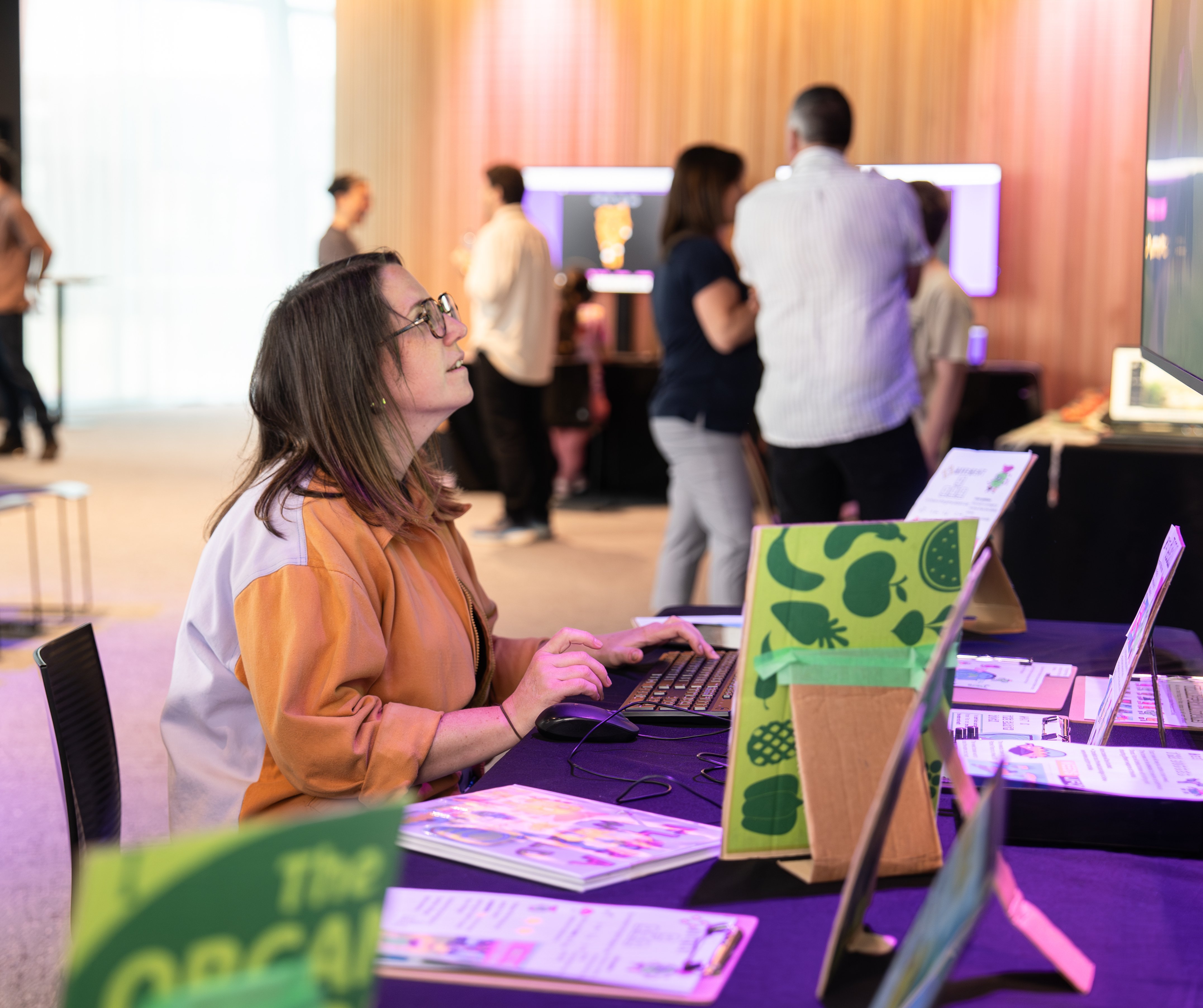 A teacher sits at a desk playing a video game created by a student.