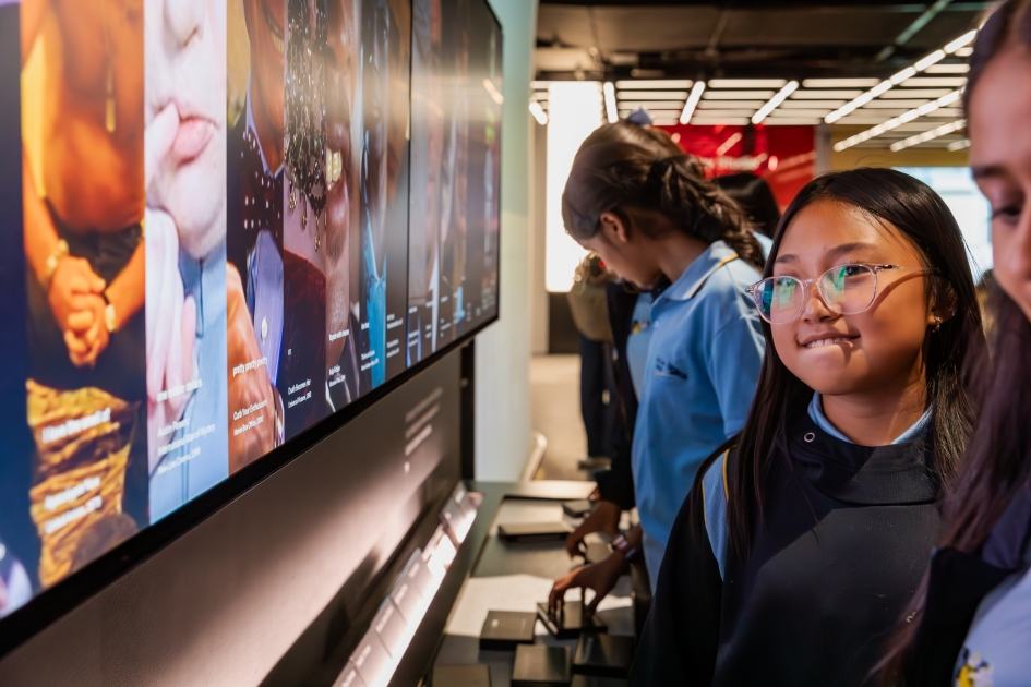 A schoolgirl with glasses looks at the editing wall in the Story of the Moving Image