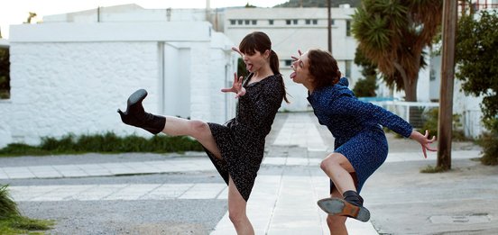 Two women outside dancing and pulling funny faces.