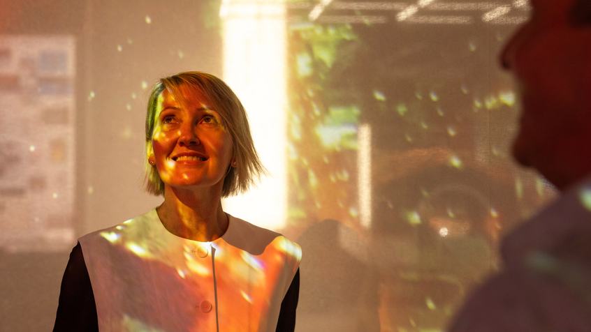 Woman standing under multicoloured light. Image credit: Charlie Kinross