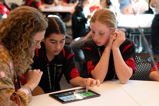Educator and two students discuss work on iPad