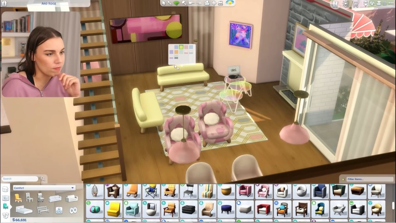 A simmer live-streaming a renovation in the sims 4. She has an interior with pastel pinks showing a split level.