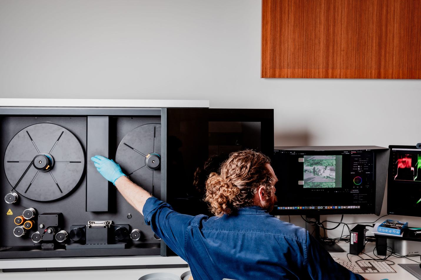 A man is operating a reel to reel film digitising machine