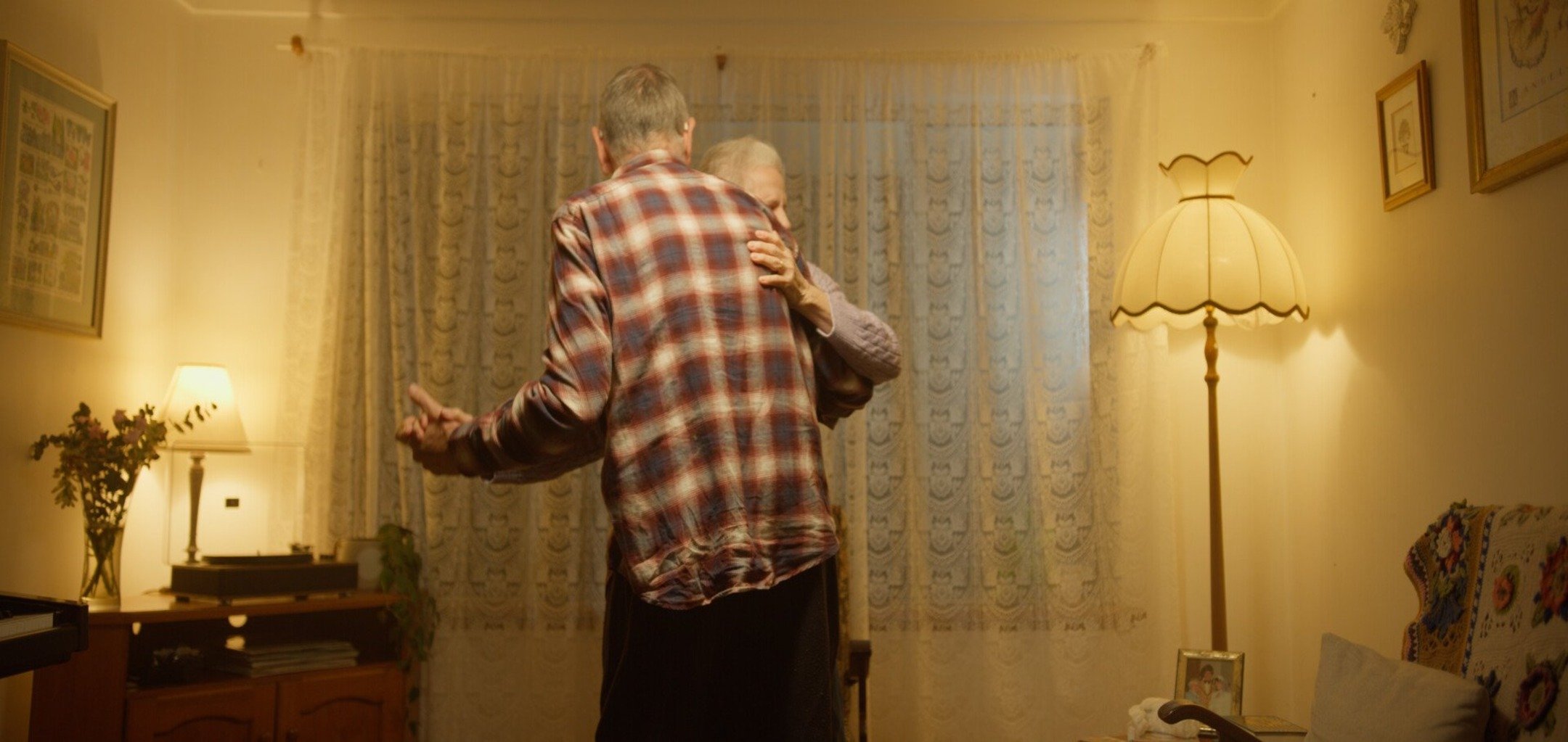 Two people embrace in a living room.