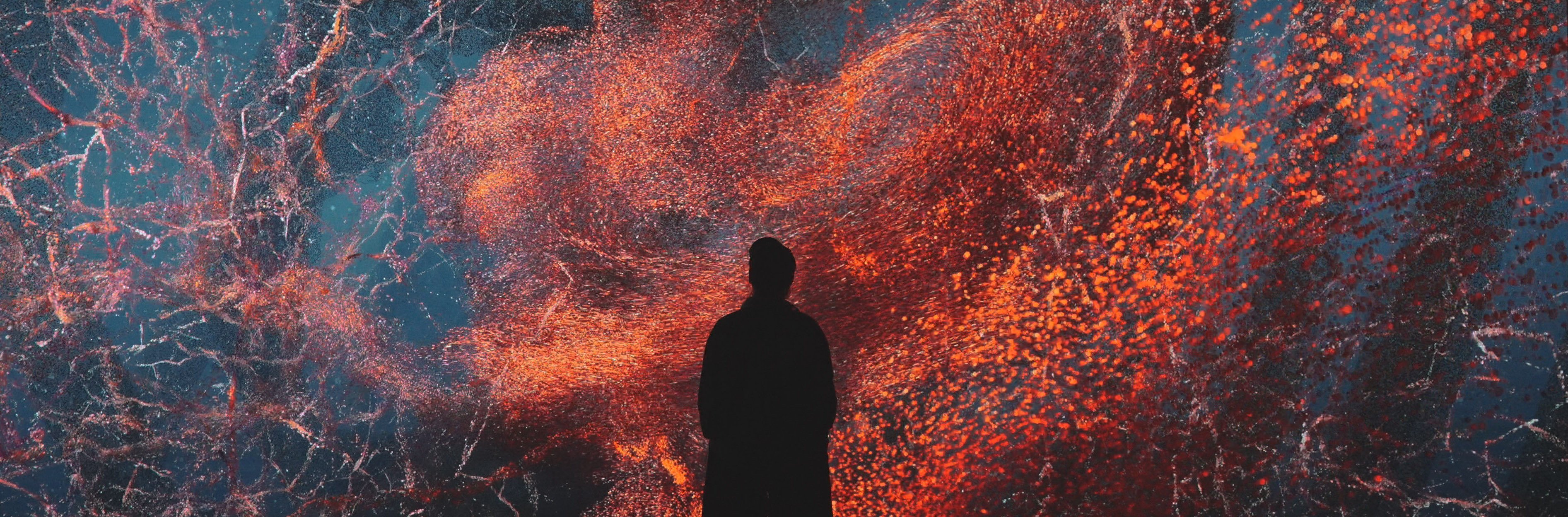 Bright burst of colour projected in dark space with silhouette of person in front of projection