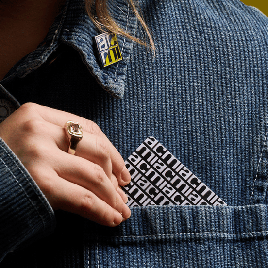 A hand holding an ACMI Member card with exclusive enamel pin