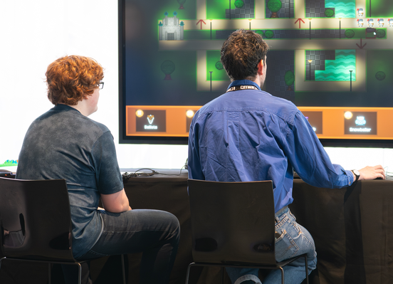 A Young Creator's Lab participant watches on as an ACMI staff member plays their videogame