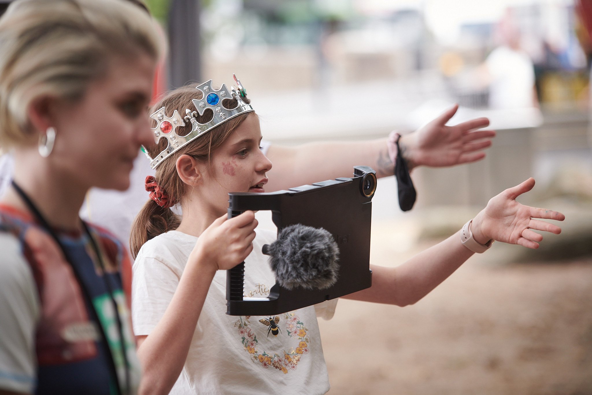 A young girl in a costume silver crown creating a film using a smartphone camera at ACMI.