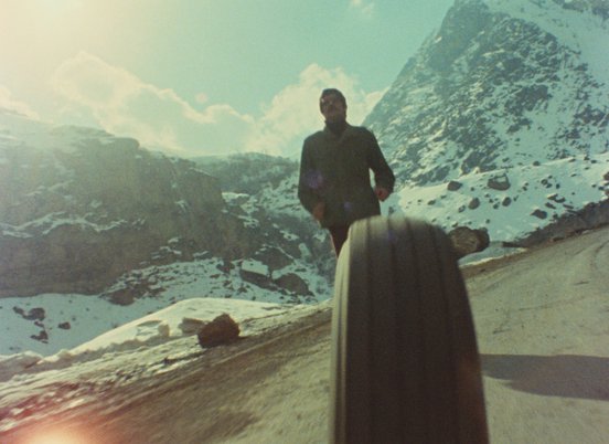 Man rolling a tyre down a hill in a still from Solution (1978) (c) Kanoon.jpg