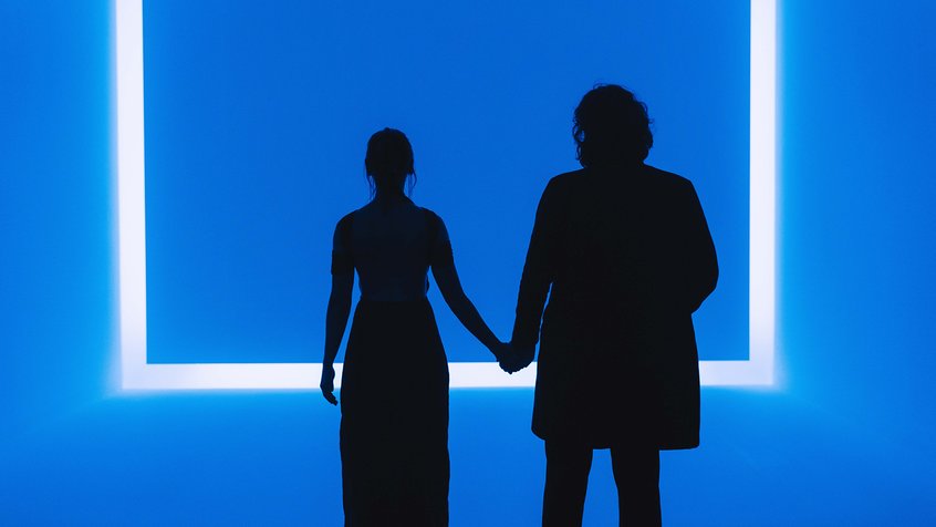 A silhouetted male and female couple holding hands in front of Raemar Blue