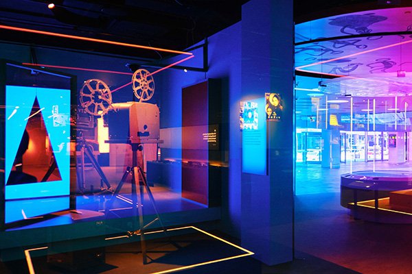 A wide shot of ACMI's centrepiece exhibition, The Story of the Moving Image, as seen through multicoloured glass