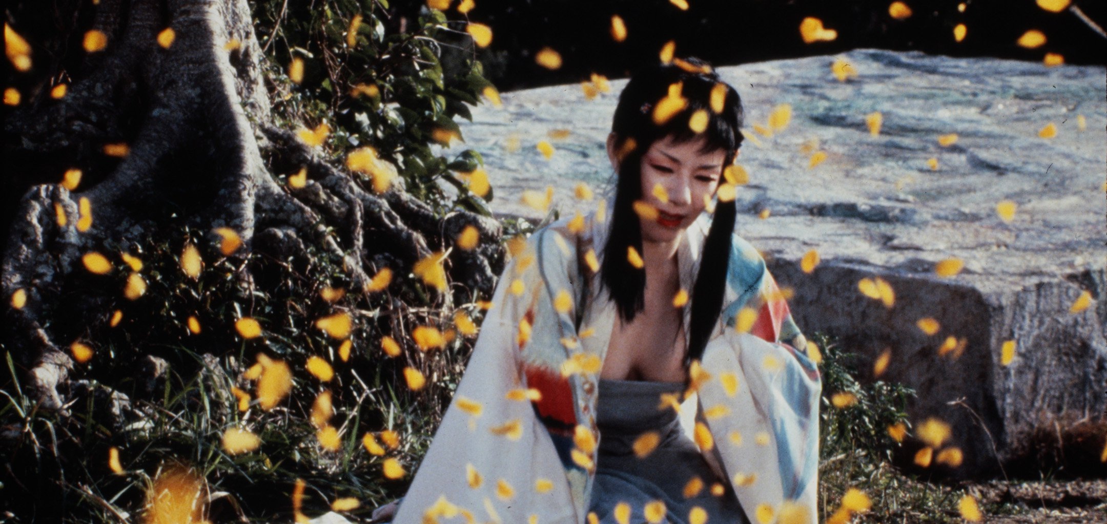 A woman in a kimono kneeling and crying as leaves fall in the foreground - still from 'Farewell to the Ark' (1984)