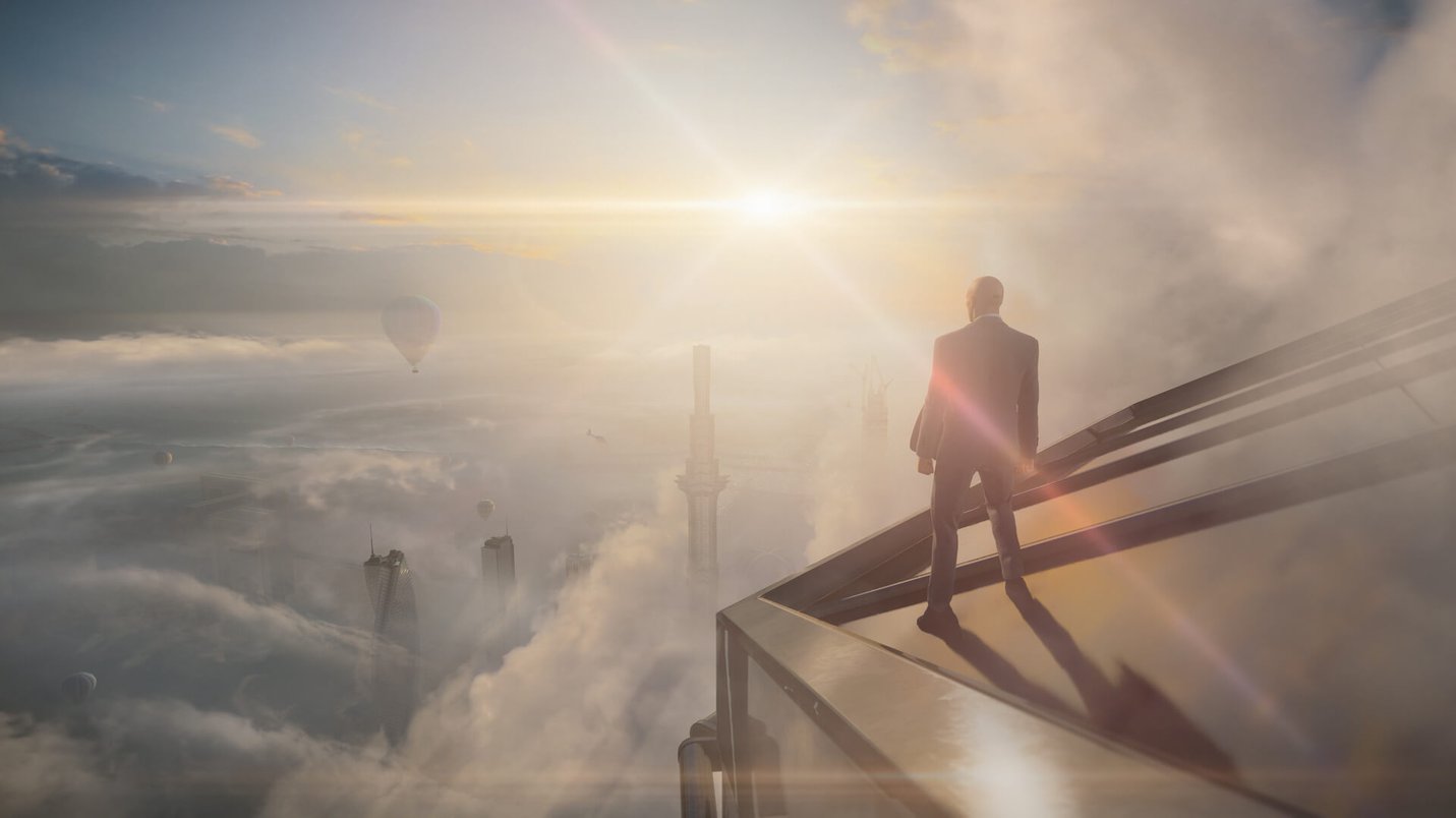 Agent 47 standing on a tower above the clouds - screenshot from 'Hitman 3' (2021)