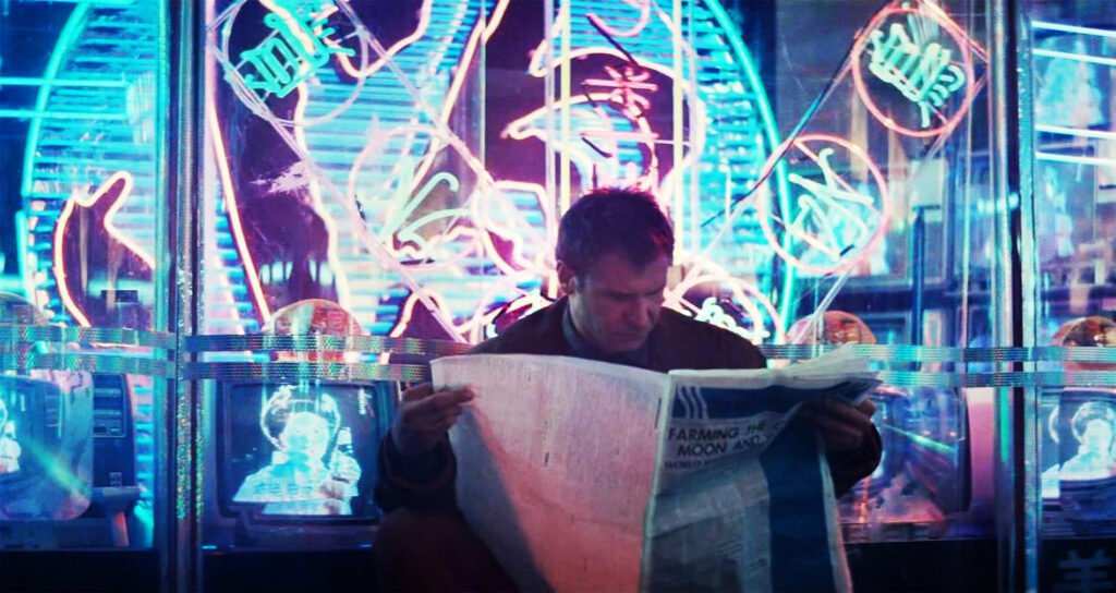 Harrison Ford as Rick Deckard in Blade Runner, wearing a trench coat and sitting outside a store reading a newspaper, with intense blue and pink neon tubes behind him, as well as TV screens.
