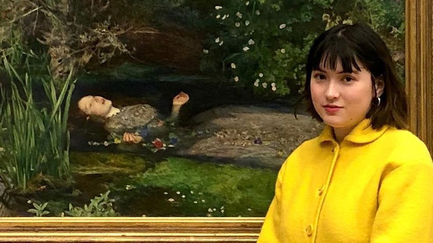 A headshot of Games Club host Claire Osborn-Li standing in front of a painting