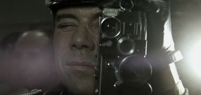 Dirk Bogarde looks through a camera in a scene from The Night Porter (1974)
