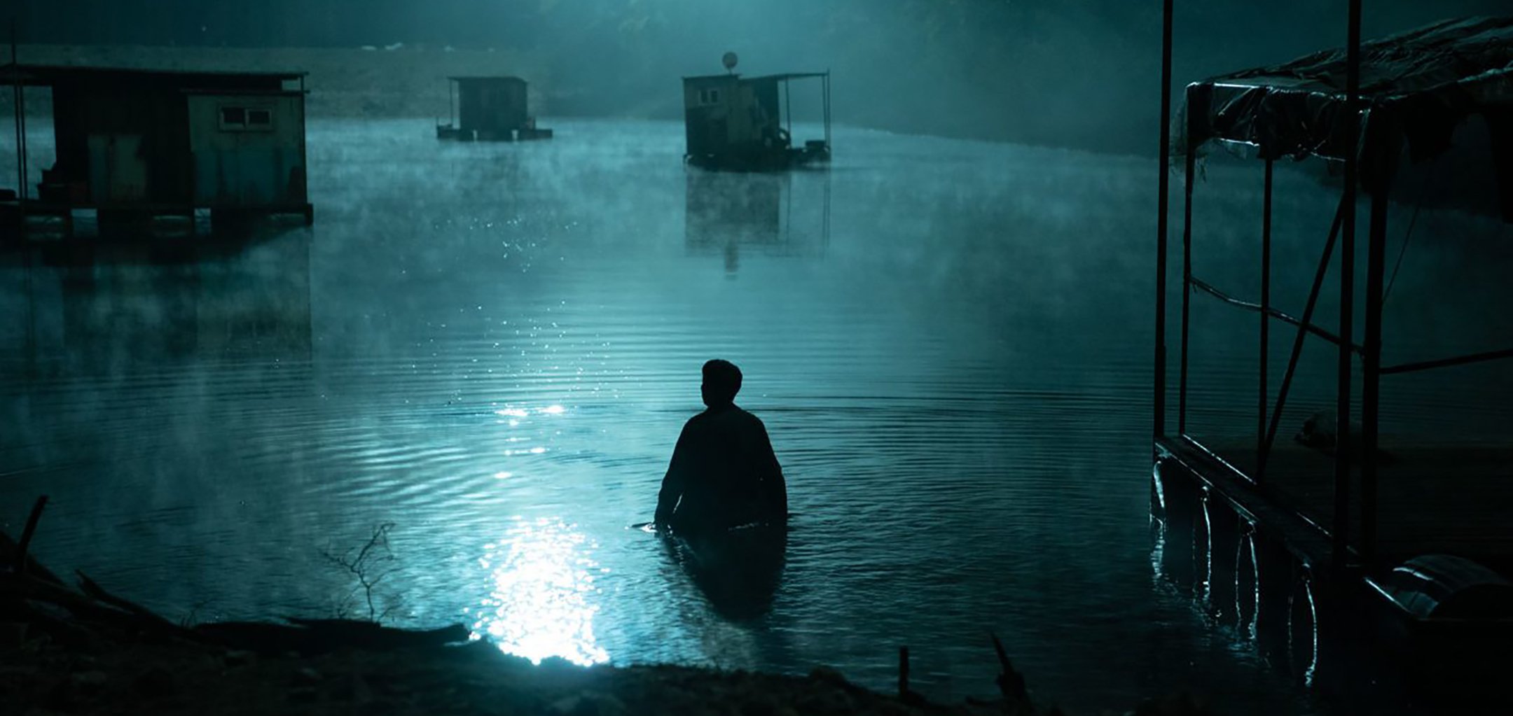 Still of silhouetted man wading in shallow foggy water from 'Hellbound' (2021) Netflix