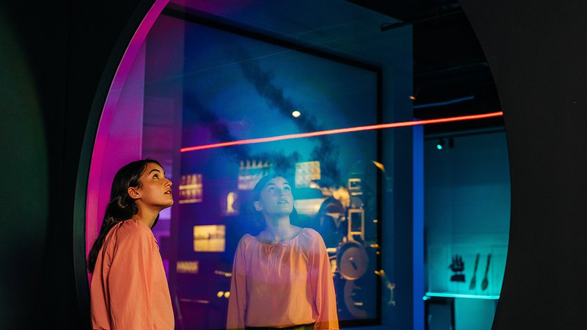 Young woman in The Story of the Moving Image at ACMI looking through glass