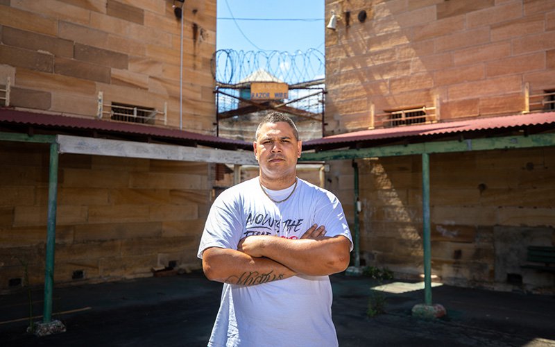 Keenan Mundine stands outside a prison in a still from 'Incarceration Nation' (2021, courtesy (incarcerationnation.com.au)