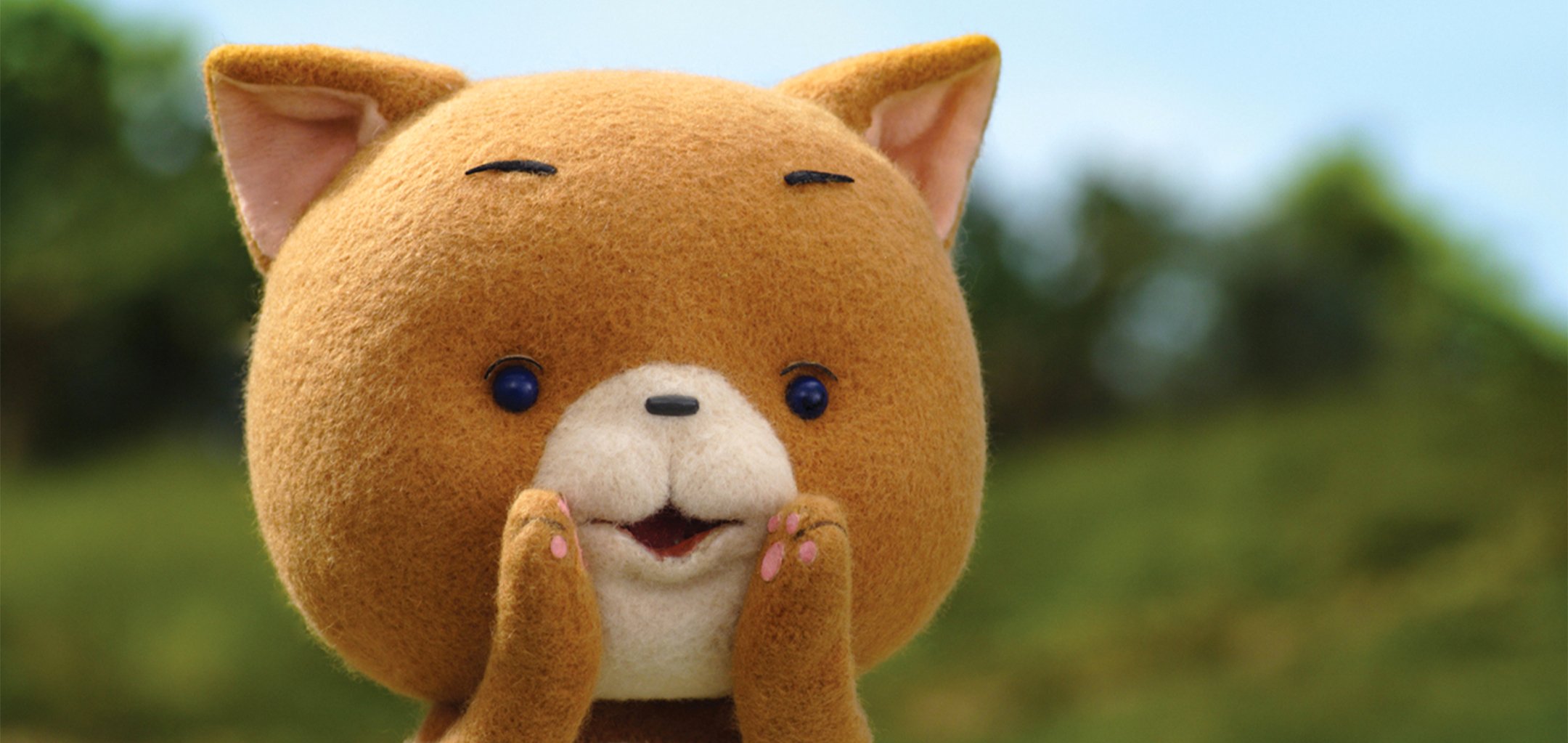 A closeup of a fuzzy cartoon cat holding its paws up to its mouth.