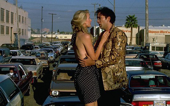 Laura Dern and Nicholas Cage stand on top of cars in a traffic jam - still from 'Wild At Heart' 1990