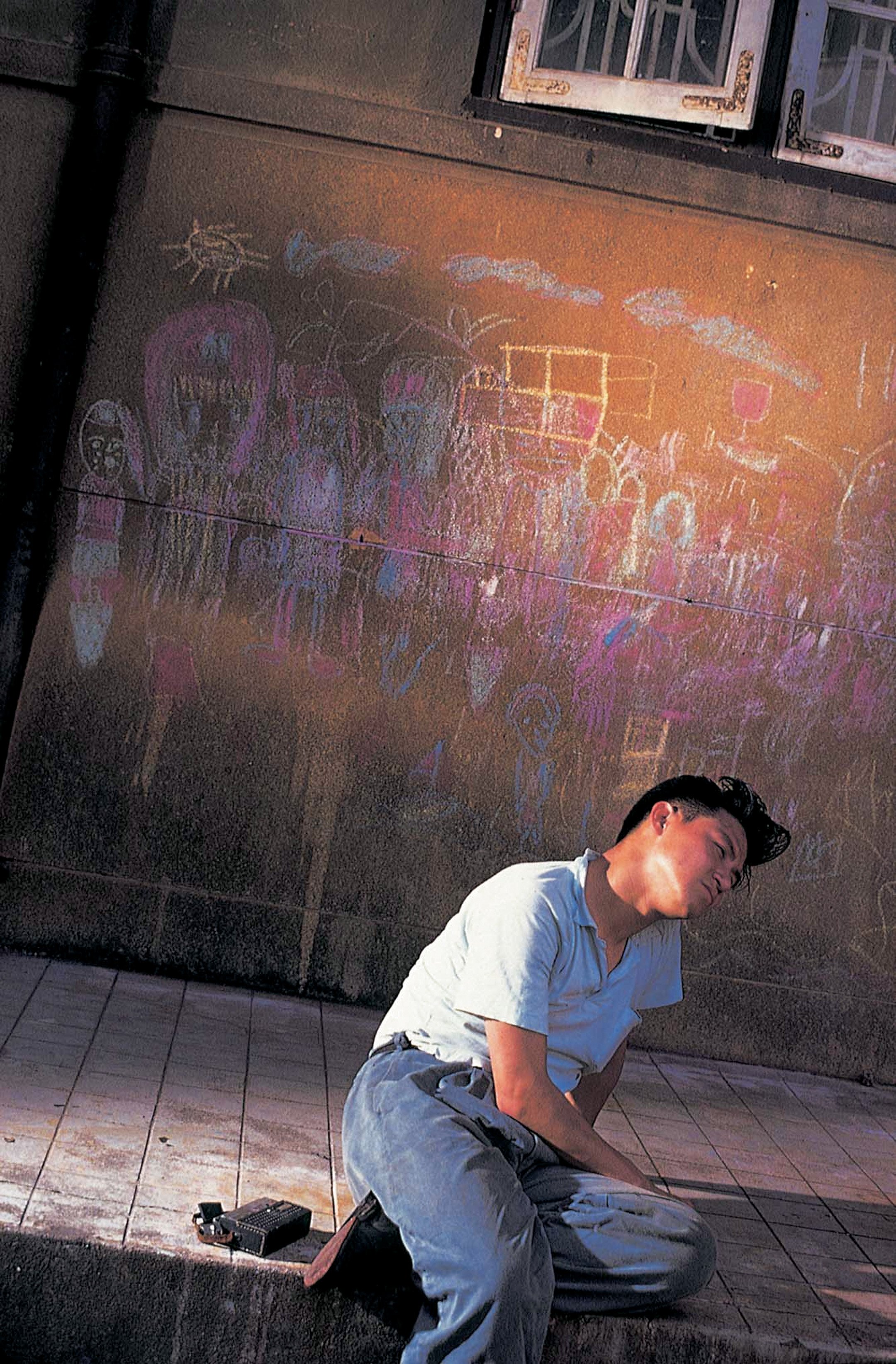 Leslie Cheung in Days of Being Wild - sitting in front of a walk with chalk drawings.jpg