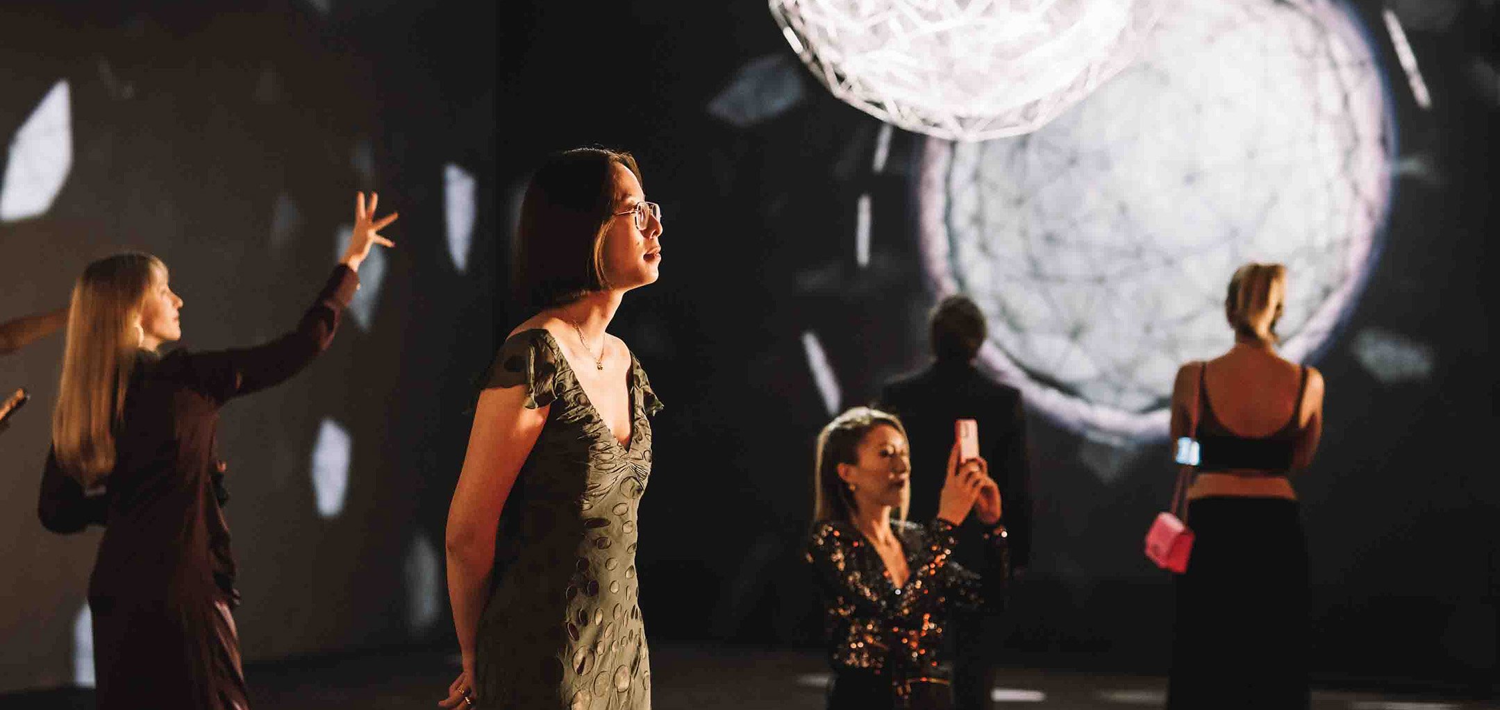 A group of women admiring Olafur Elaisson's Stardust Particle installation at Light: Works from Tate's Collection exhibition at ACMI.