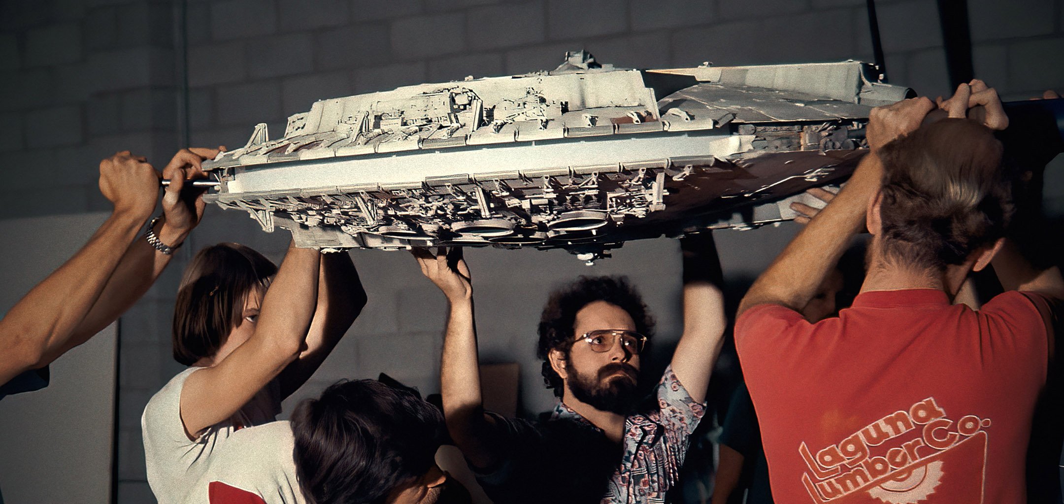 The crew of Star Wards holding up the Millennium Falcon model - still from Light and Magic (Disney+)