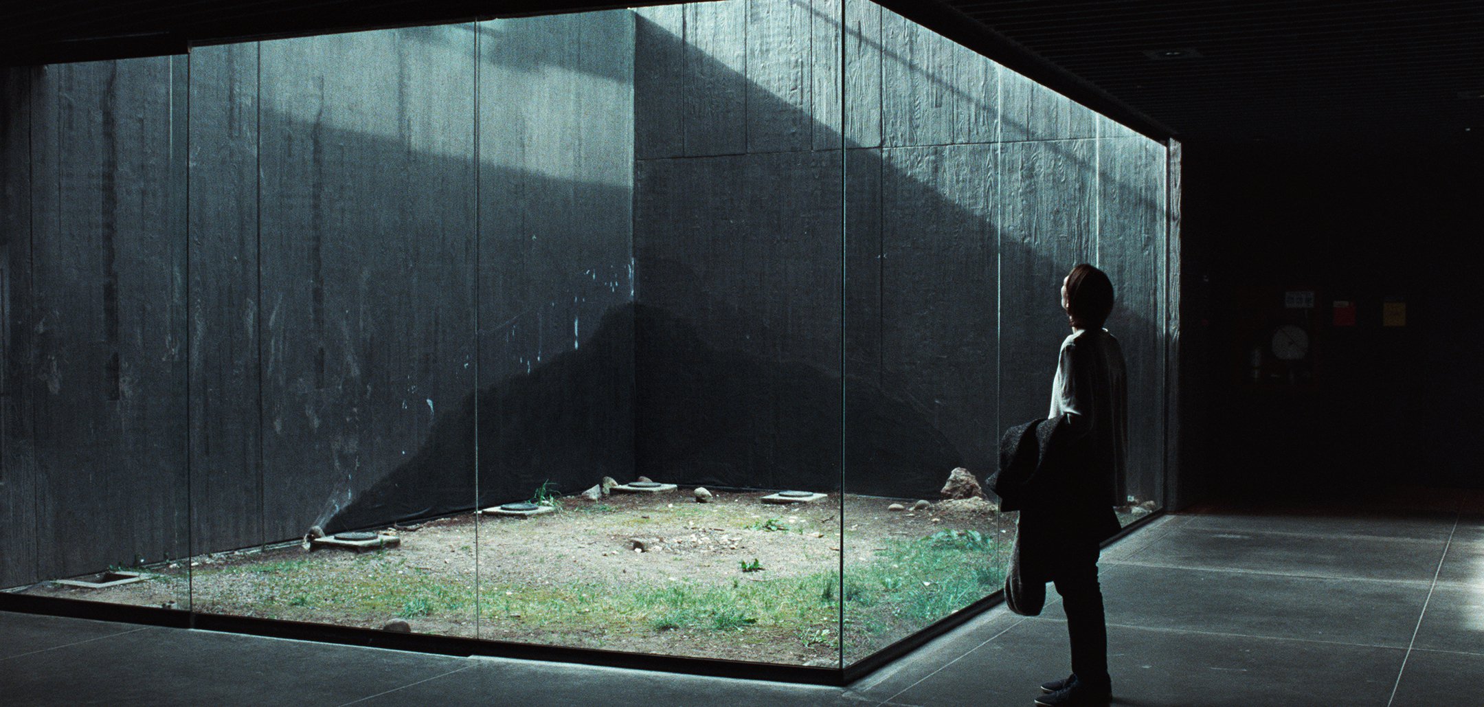 Tilda Swinton looking at a glass cube in a still from Memoria (2021)