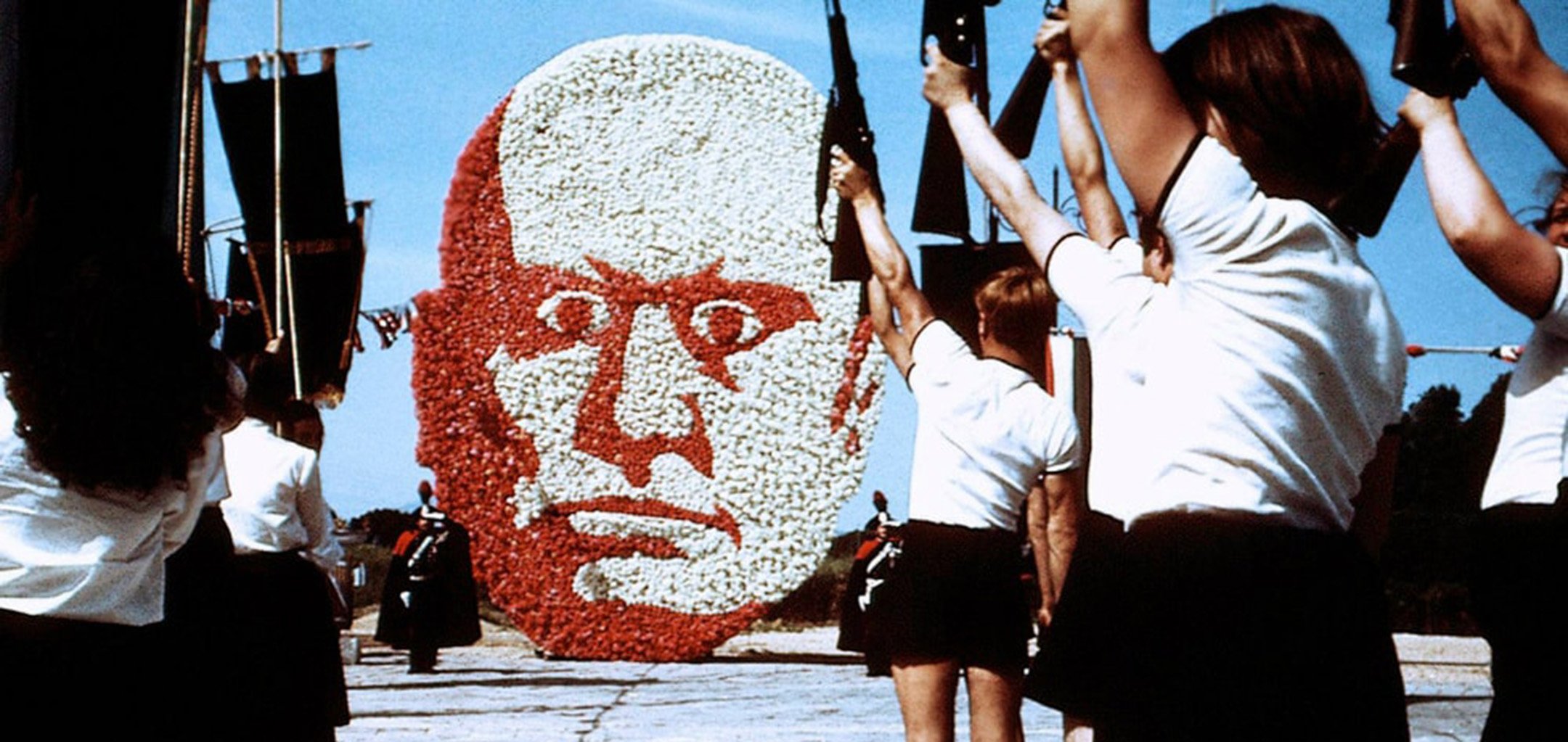 Mussollini mural with kids holding up guns - still from Amarcord (1973)