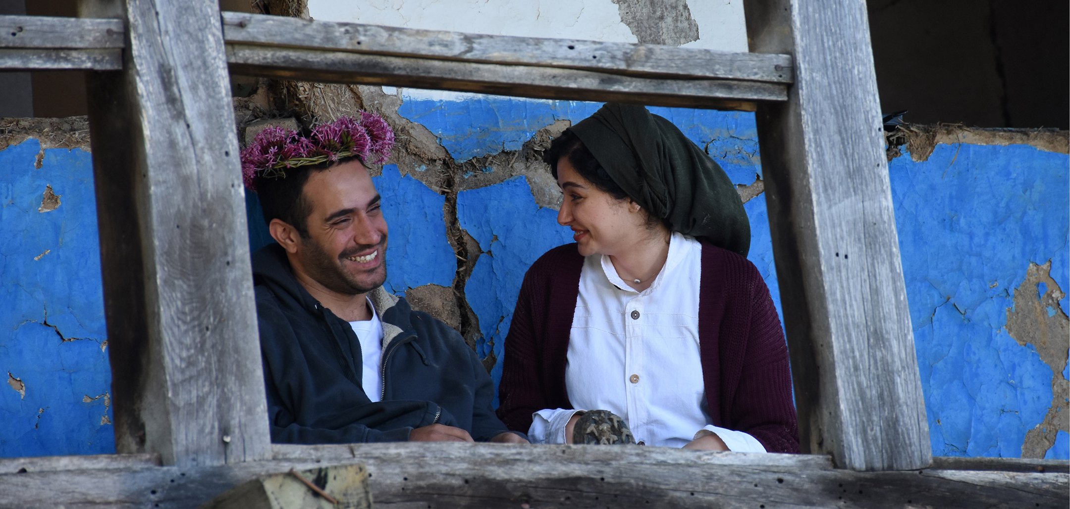 Mohammad Valizadegan and Baran Rasoulof smiling as Mohammad wears a flower crown in a still from 'There Is No Evil' (2020)