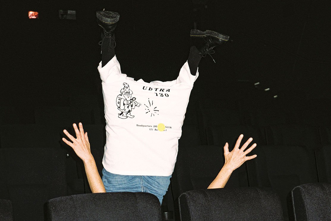 A person wears a T-shirt on their legs upside down in a cinema - promotional image for the ACMI x Kloke collaboration