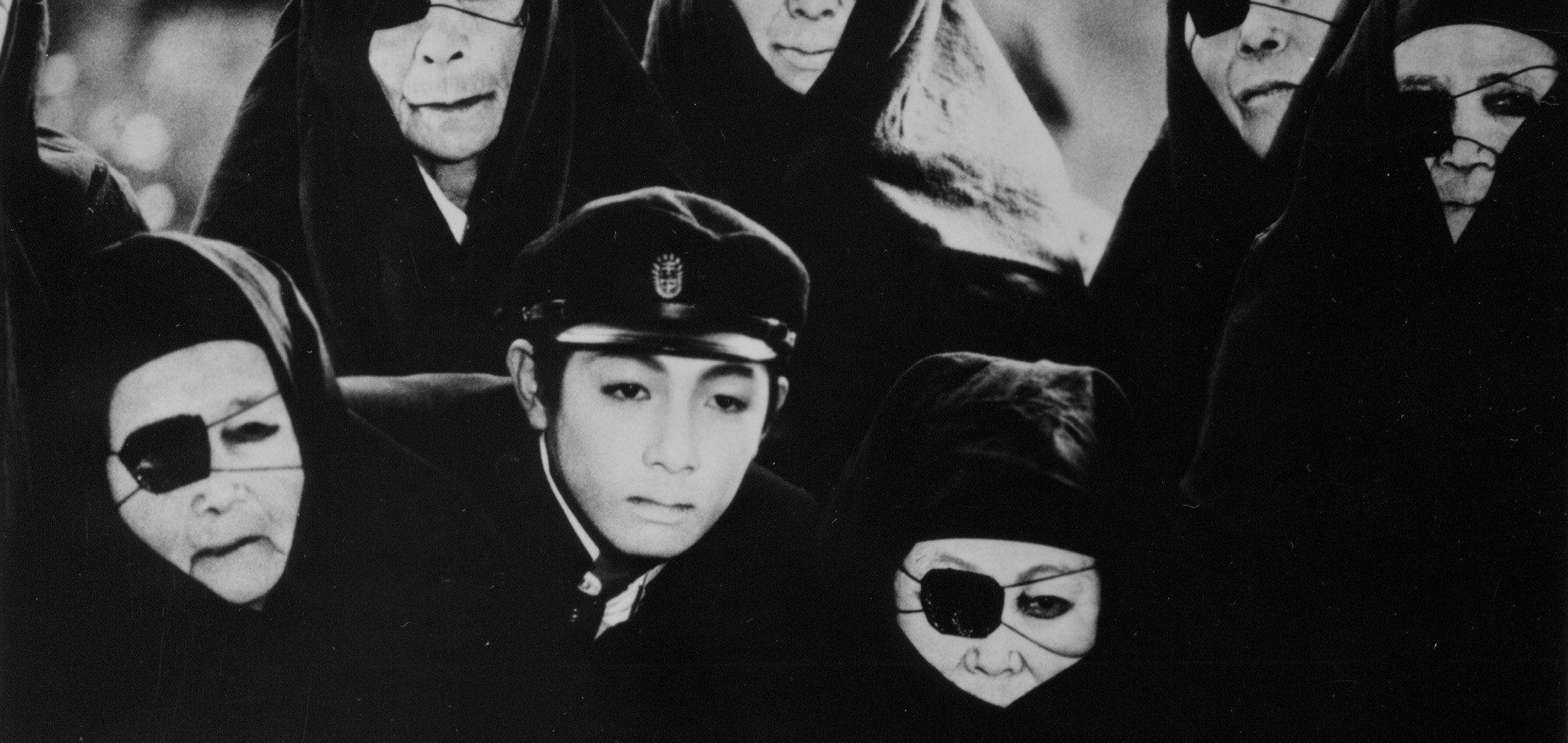 Young boy surrounded by elderly women with eye patches and in robes in 'Pastoral Hide-and-Seek' (1974)