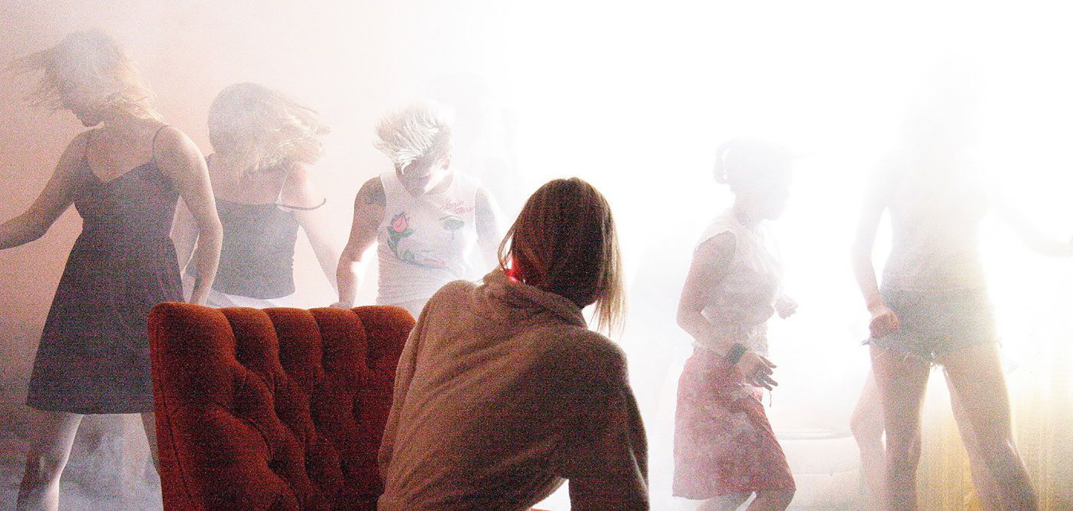 Five actresses dance behind Laura Dern's chair in a hazy room - still from 'Inland Empire' (2006)