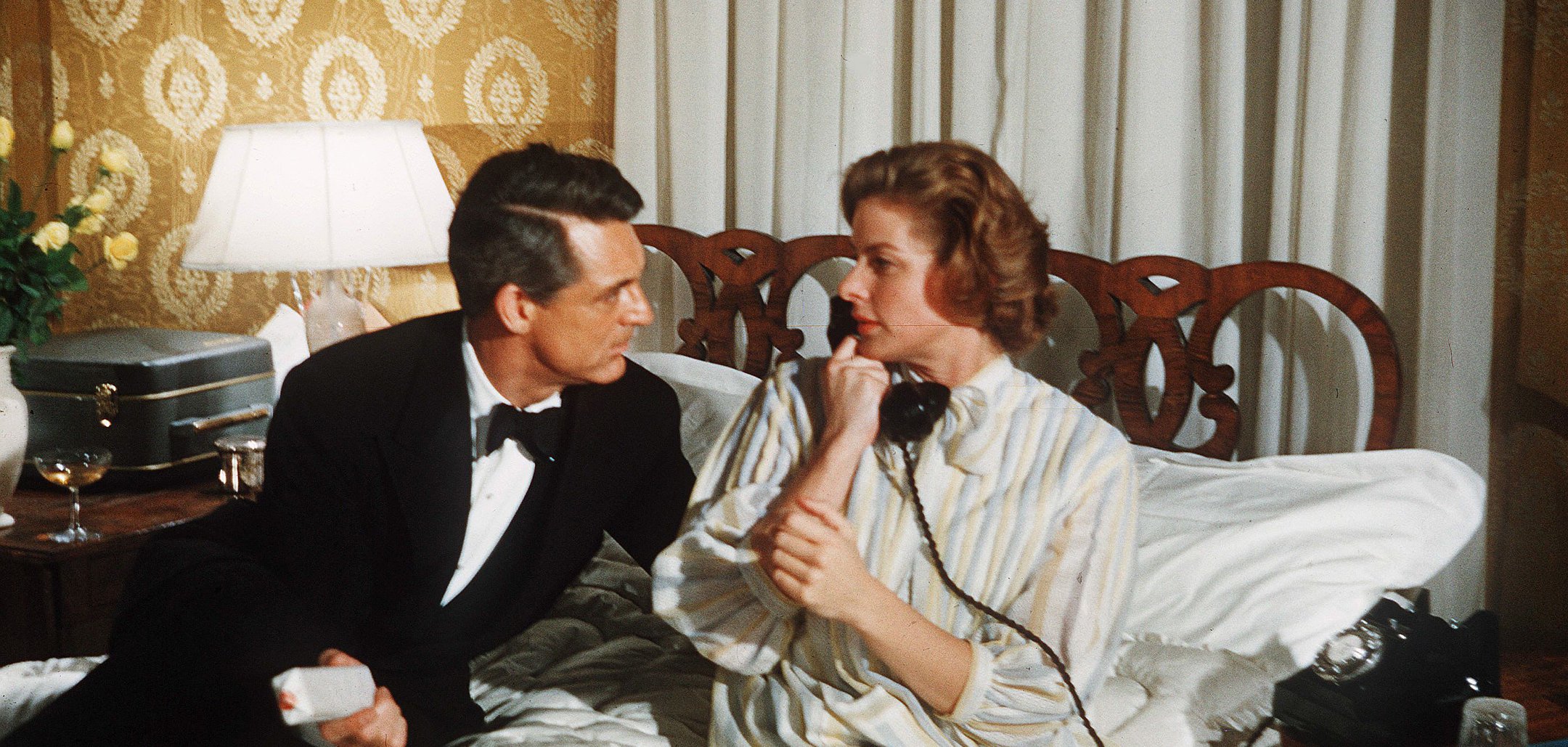 Cary Grant and Ingrid Bergman sit on a bed and look into each others' eyes in a still from 'Indiscreet' (1958)