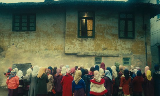 Kids in headscarves crowding around a building in a still from 'The Chorus' (1982)